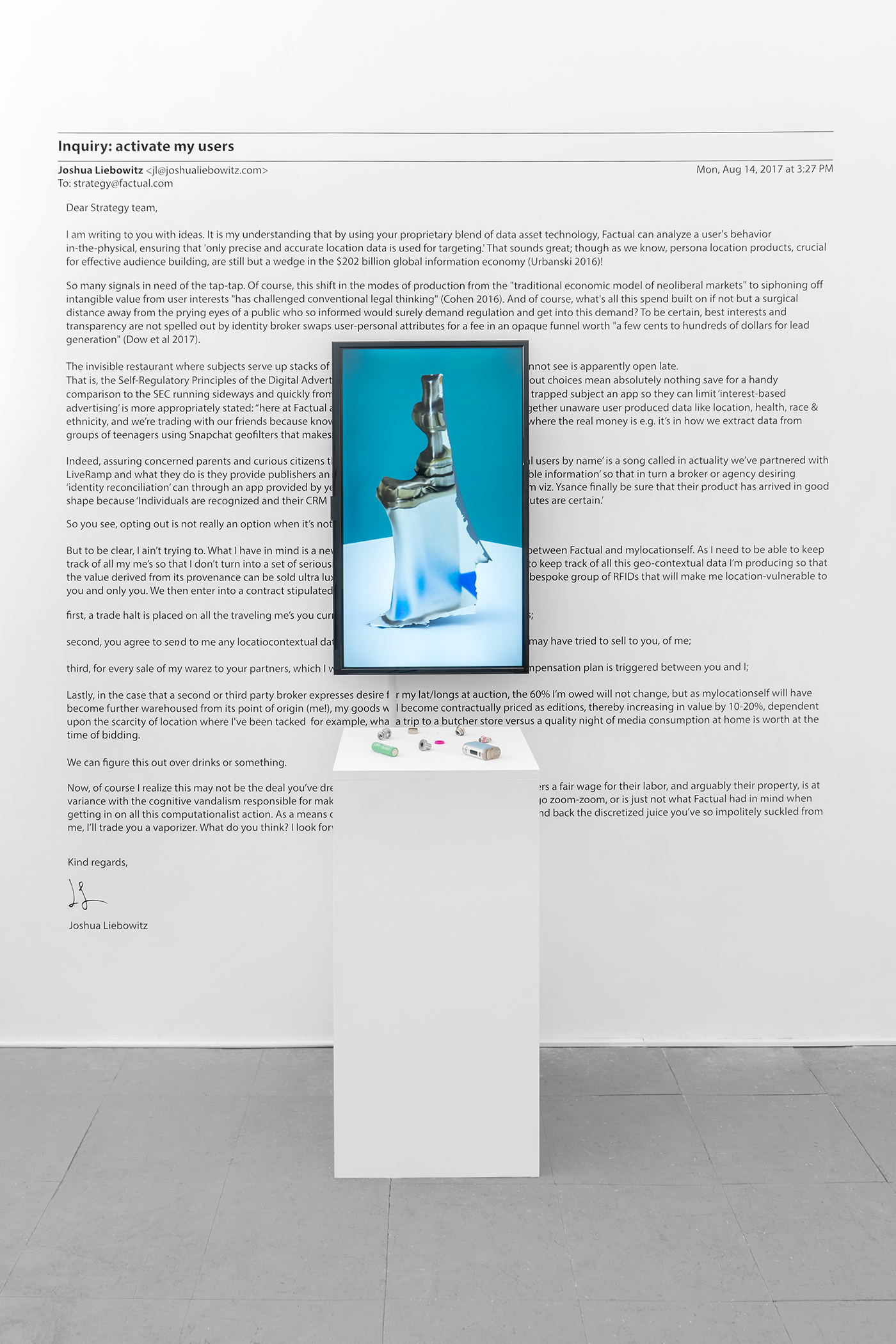 Assemblage of vaporizer parts on pedestal, digital still on monitor, and vinyl text of electronic mail on wall