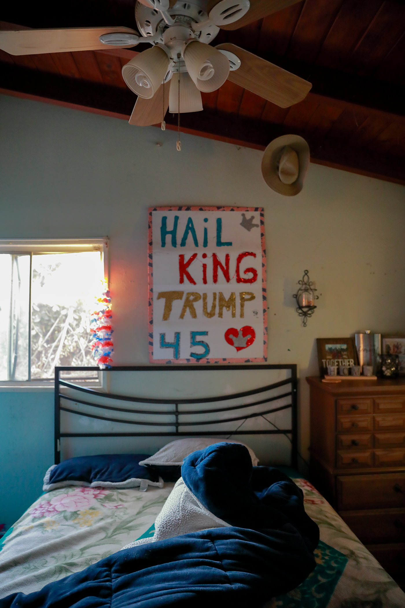 Photograph of bedroom in La Puente, California showing homemade banner above bed, which reads "Hail King Trump, 45"